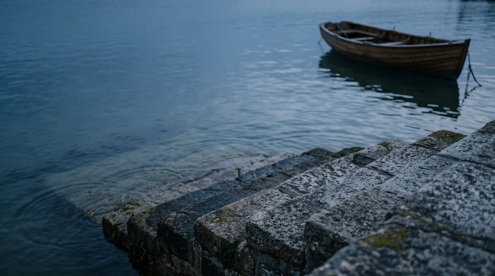 Stone harbor steps descending into calm water at dusk, the waterline partway up the steps